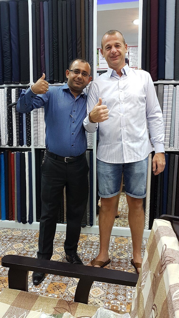 A happy client with the tailor after collecting his shirts