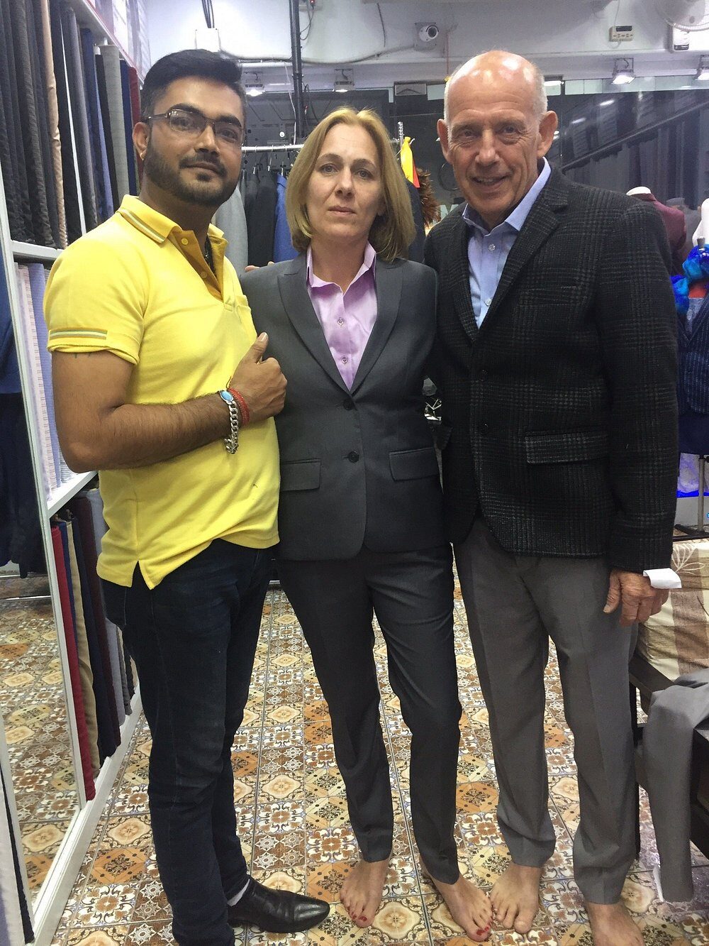 A couple in their finished tailoring — a grey suit for her, a checked jacket for him