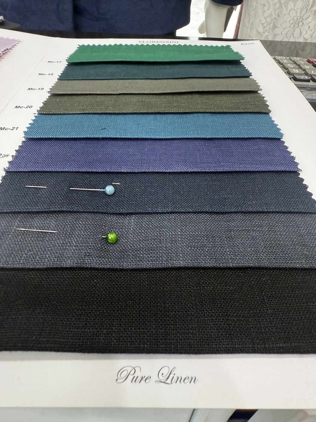 A Pure Linen swatch book open on the table, greens to navy