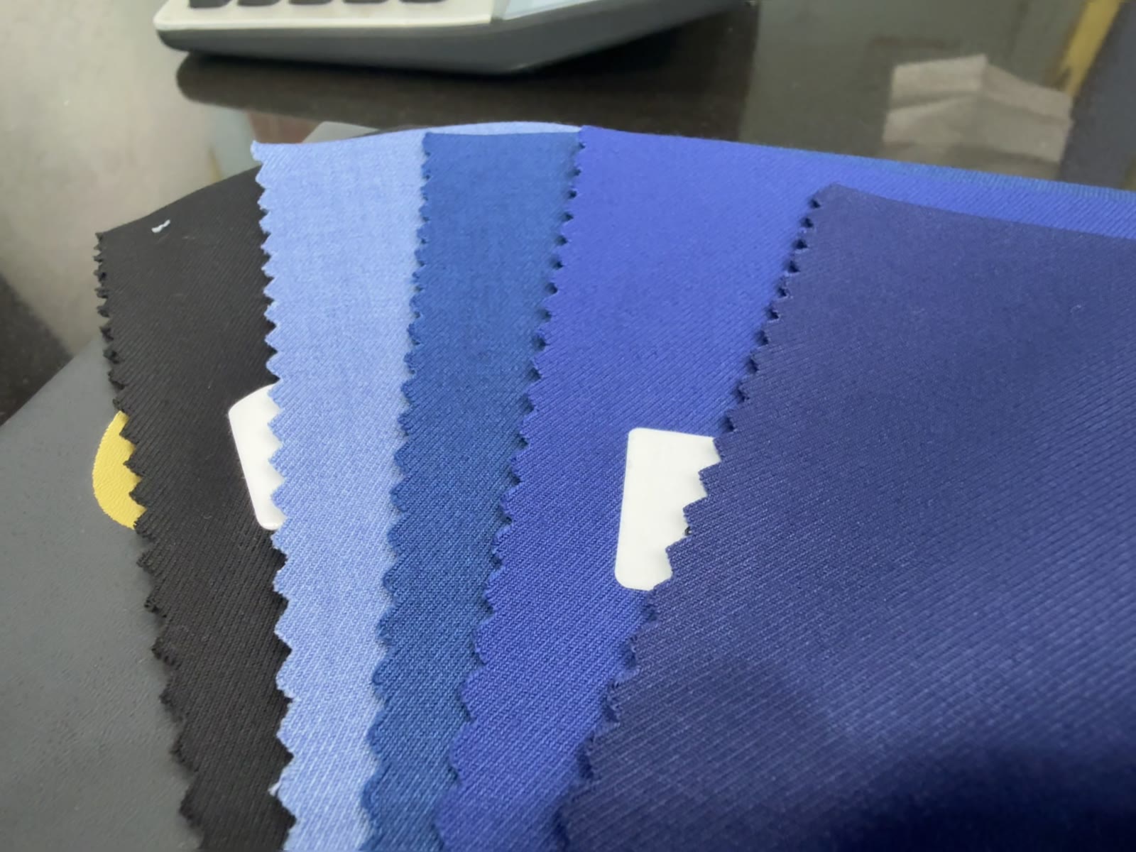 A fan of blue suiting swatches, from sky to midnight